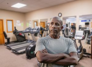 Fit African American man with Pacific Rehabilitation Centers therapy gym in background
